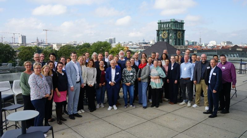 Gruppenfoto der Teilnehmenden auf der Dachterasse beim Zukunftscluster MCube mit Blick über München.